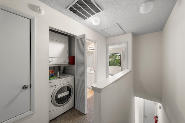 clothes washing area with carpet flooring, a textured ceiling, and stacked washer / drying machine