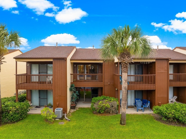 rear view of property with a yard, a balcony, and a patio