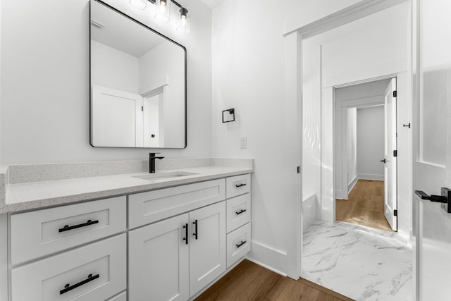 bathroom with vanity, a bath, and hardwood / wood-style flooring