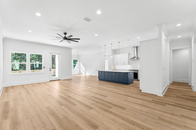 unfurnished living room featuring ceiling fan, ornamental molding, sink, and light hardwood / wood-style flooring