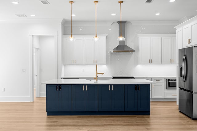 kitchen with wall chimney exhaust hood, white cabinetry, stainless steel appliances, and decorative light fixtures