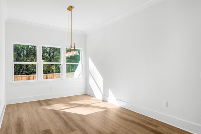 empty room with light hardwood / wood-style floors and crown molding