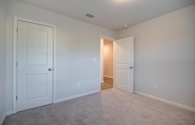 unfurnished bedroom featuring a closet and light colored carpet