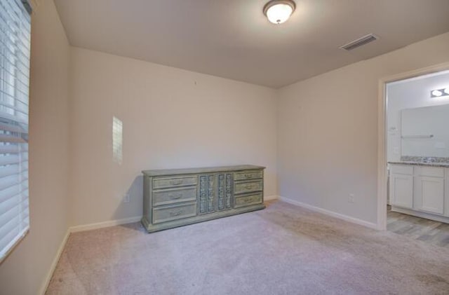 unfurnished bedroom with light carpet and connected bathroom