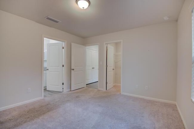 unfurnished bedroom featuring light carpet, a closet, and a spacious closet