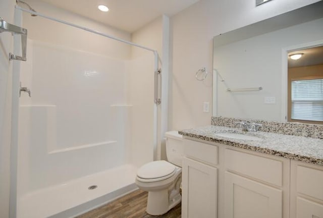 bathroom featuring hardwood / wood-style floors, vanity, toilet, and walk in shower