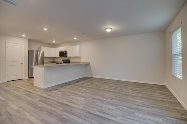 kitchen featuring kitchen peninsula, white cabinetry, light hardwood / wood-style floors, and appliances with stainless steel finishes