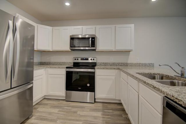 kitchen with light stone countertops, white cabinetry, sink, and stainless steel appliances