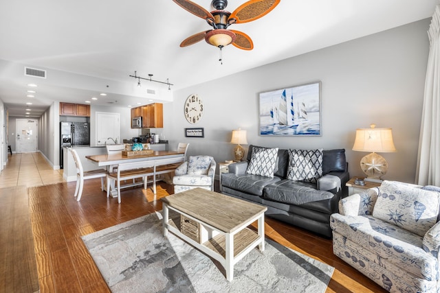 living room featuring light hardwood / wood-style floors, track lighting, and ceiling fan