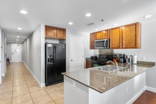 kitchen featuring sink, kitchen peninsula, stone countertops, light tile patterned flooring, and black appliances