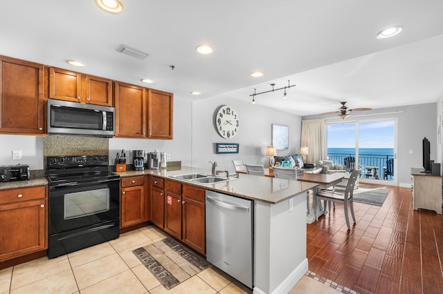 kitchen with light hardwood / wood-style floors, kitchen peninsula, sink, and appliances with stainless steel finishes