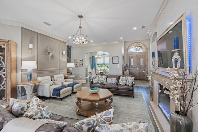 living room featuring hardwood / wood-style flooring, a notable chandelier, and ornamental molding