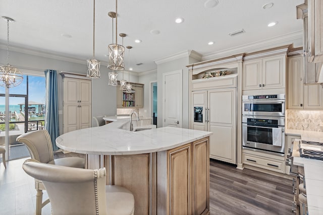 kitchen featuring a breakfast bar area, an island with sink, pendant lighting, and paneled refrigerator