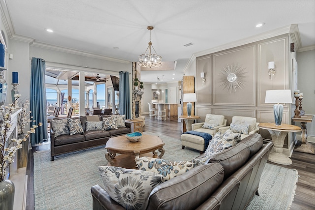 living room with ceiling fan with notable chandelier, hardwood / wood-style flooring, and ornamental molding