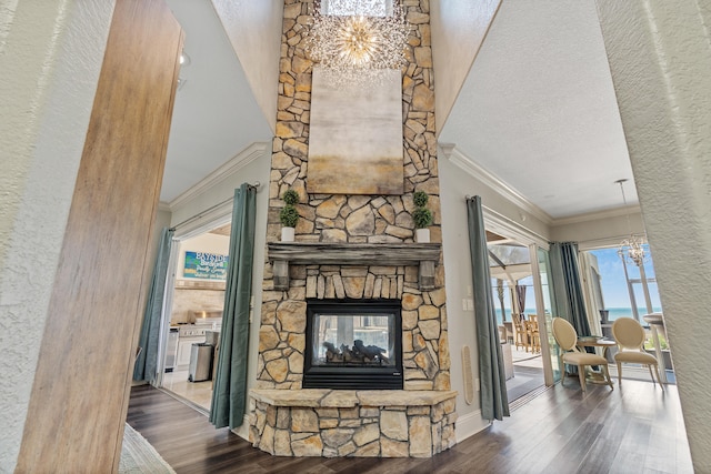 living room featuring a stone fireplace, ornamental molding, a textured ceiling, and hardwood / wood-style flooring