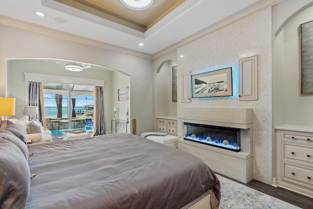 bedroom with dark hardwood / wood-style floors, a water view, crown molding, and access to outside