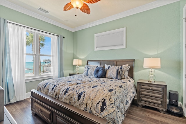 bedroom featuring ceiling fan, crown molding, a water view, and dark wood-type flooring