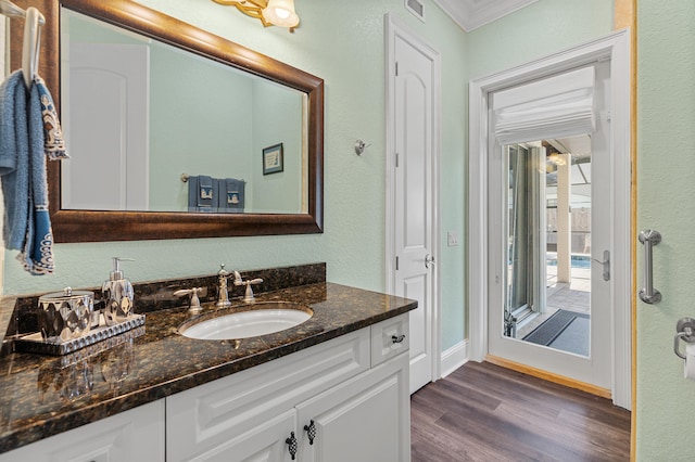 bathroom featuring vanity, hardwood / wood-style flooring, and crown molding