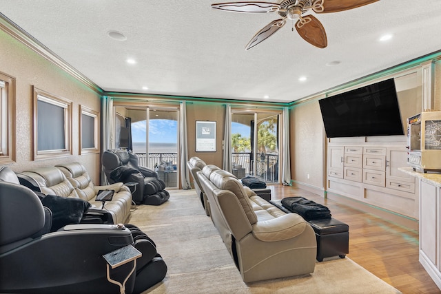 living room featuring crown molding, ceiling fan, a textured ceiling, and light wood-type flooring