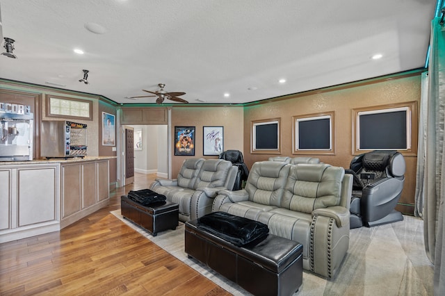 home theater with ceiling fan, light hardwood / wood-style floors, ornamental molding, and a textured ceiling