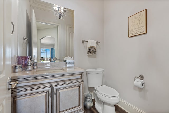 bathroom with hardwood / wood-style floors, vanity, crown molding, toilet, and a notable chandelier