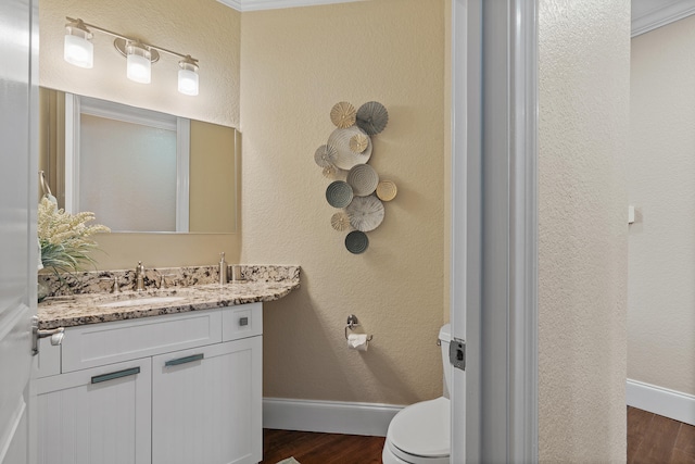 bathroom with vanity, toilet, wood-type flooring, and ornamental molding