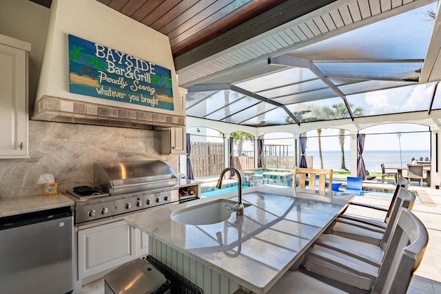 view of patio / terrace featuring sink, a pool with hot tub, a lanai, a grill, and a water view