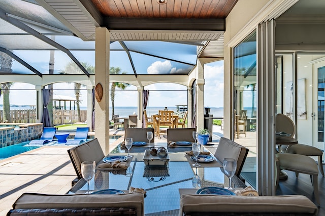 view of patio with a lanai, a pool with hot tub, and a water view