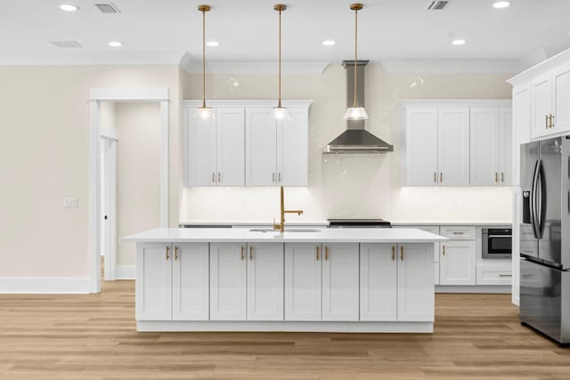 kitchen with pendant lighting, a center island with sink, white cabinets, wall chimney range hood, and appliances with stainless steel finishes