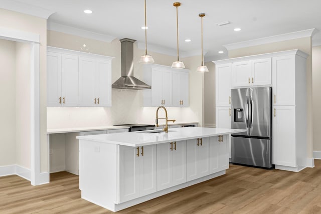 kitchen featuring white cabinetry, sink, wall chimney exhaust hood, stainless steel fridge, and a center island with sink