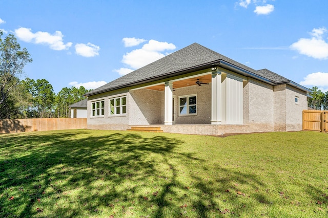 back of property featuring ceiling fan and a yard