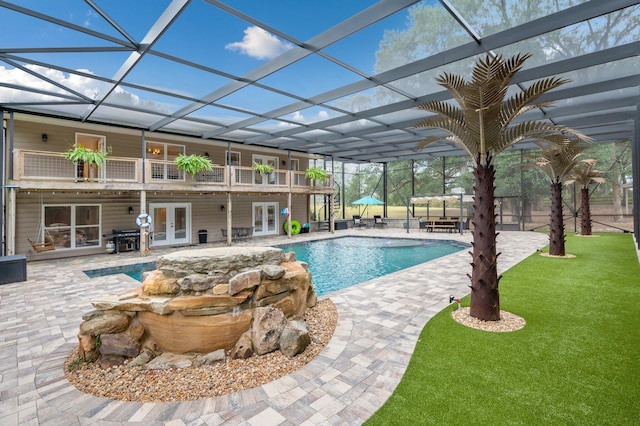 view of swimming pool with a lanai, a patio area, french doors, and a lawn