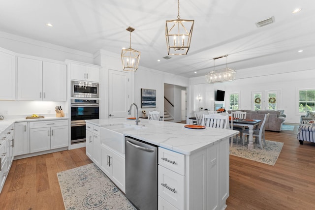 kitchen featuring a center island with sink, white cabinets, light hardwood / wood-style floors, and appliances with stainless steel finishes