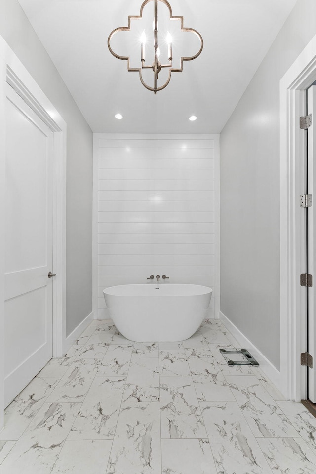 bathroom featuring a tub to relax in and an inviting chandelier