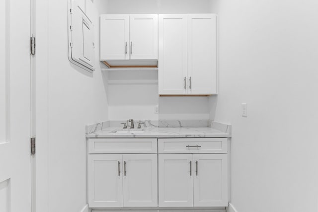 interior space featuring light stone countertops, white cabinetry, and sink