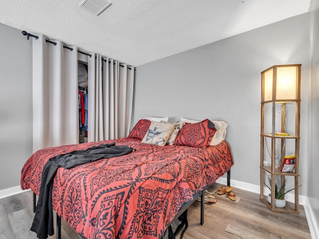 bedroom with a textured ceiling and light wood-type flooring