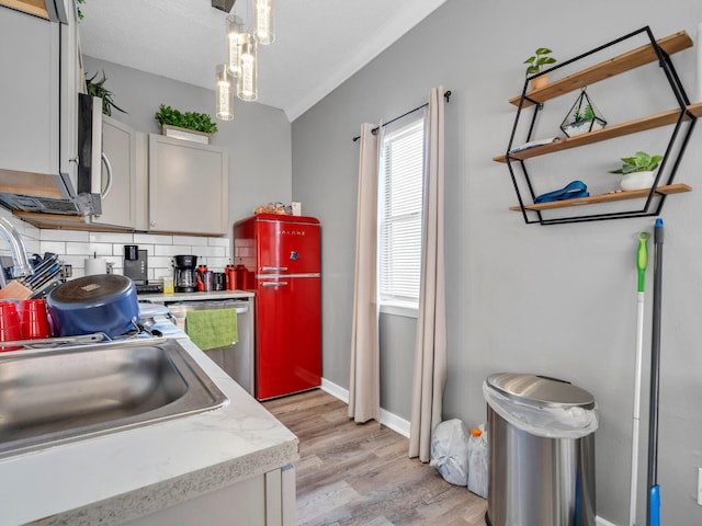 kitchen with decorative backsplash, crown molding, pendant lighting, light hardwood / wood-style flooring, and dishwasher