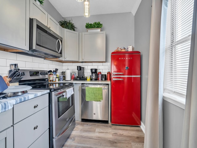 kitchen with decorative backsplash, a textured ceiling, light wood-type flooring, and stainless steel appliances