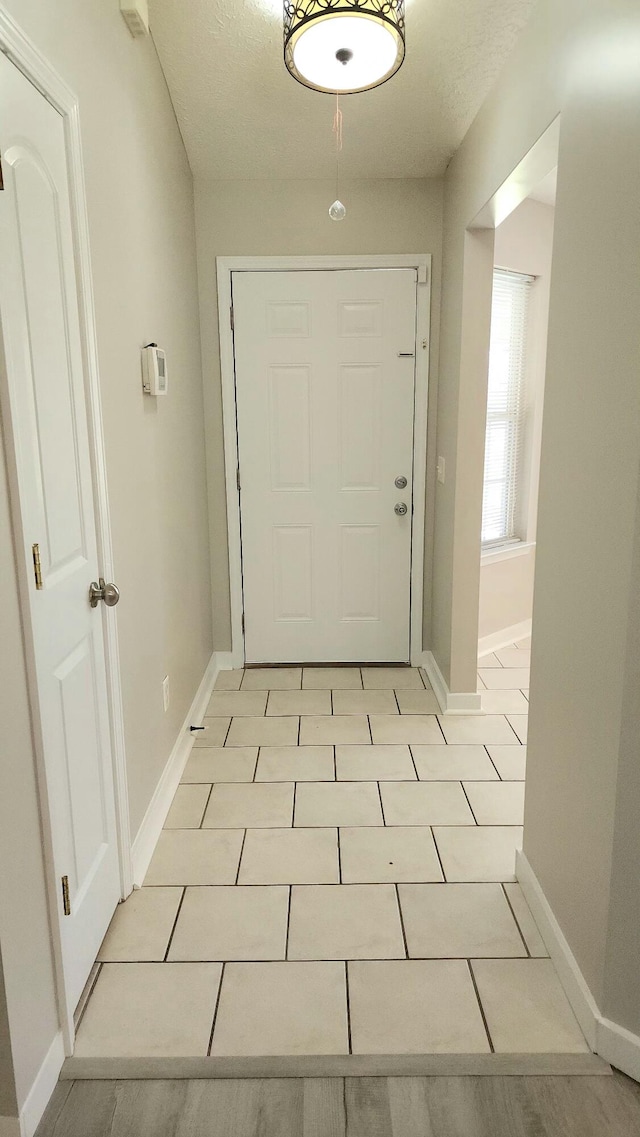 doorway featuring a textured ceiling and light tile patterned flooring