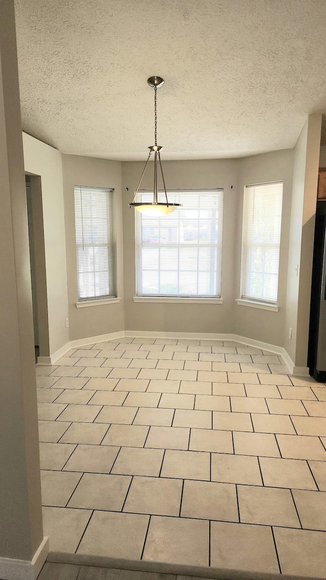 unfurnished dining area with light tile patterned floors and a textured ceiling