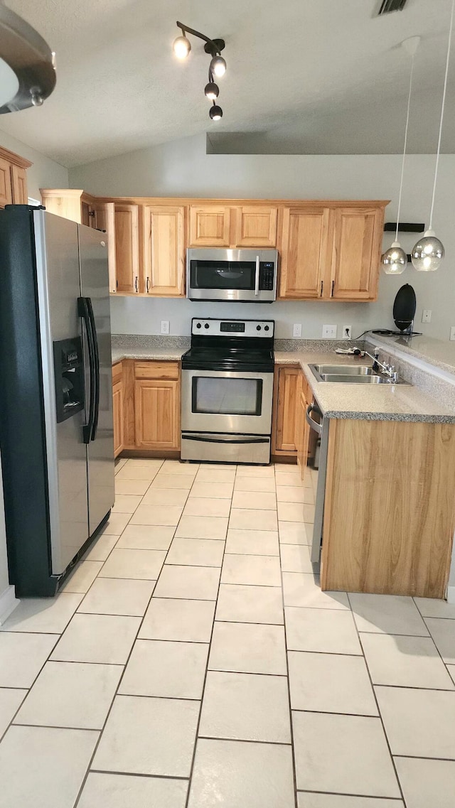 kitchen with sink, hanging light fixtures, lofted ceiling, light tile patterned floors, and appliances with stainless steel finishes