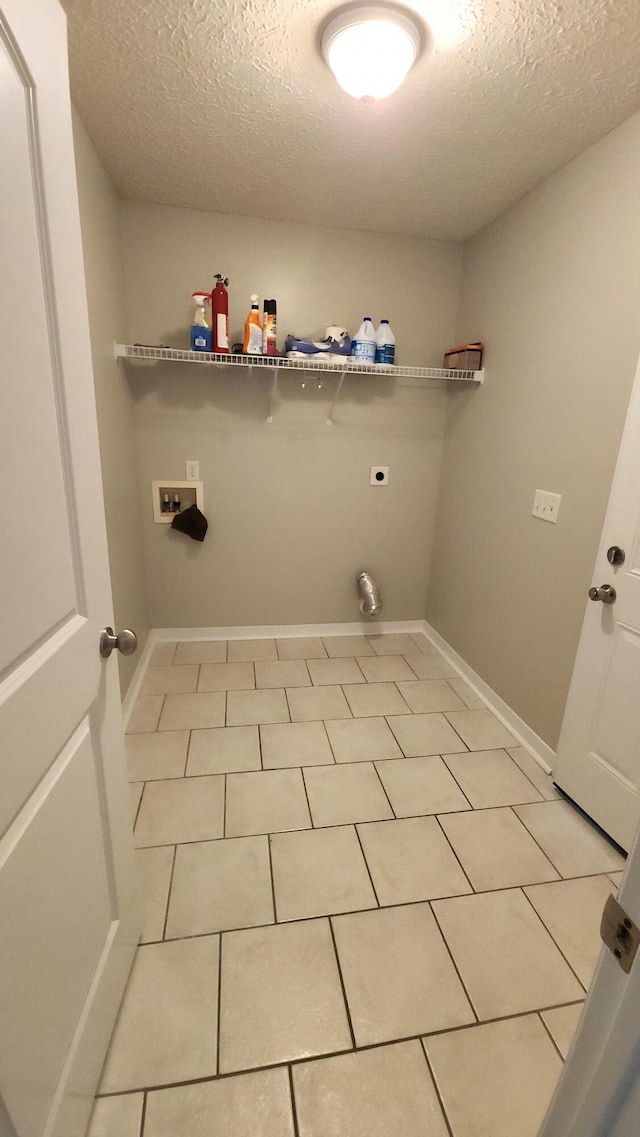 laundry area featuring electric dryer hookup, light tile patterned flooring, a textured ceiling, and hookup for a washing machine