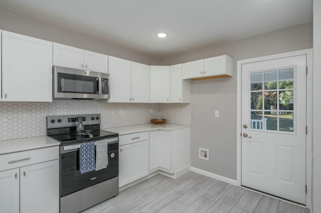 kitchen featuring white cabinetry, backsplash, appliances with stainless steel finishes, and light hardwood / wood-style flooring