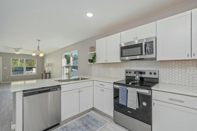 kitchen with kitchen peninsula, appliances with stainless steel finishes, sink, light hardwood / wood-style floors, and white cabinetry