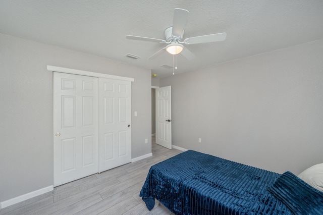 bedroom featuring ceiling fan, light wood-type flooring, and a closet