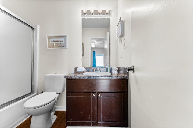 full bathroom with vanity, hardwood / wood-style flooring, ceiling fan, toilet, and enclosed tub / shower combo