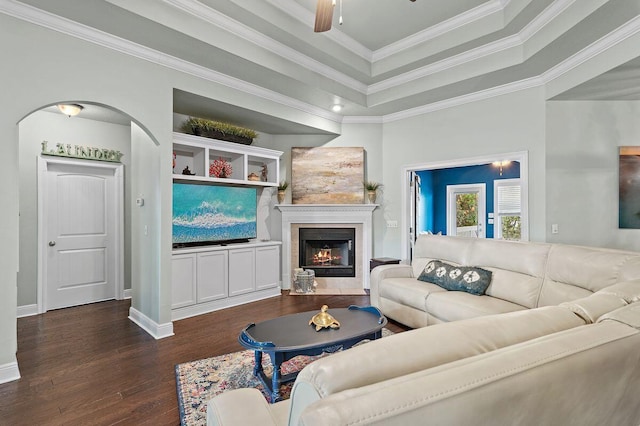 living room with dark hardwood / wood-style floors, ceiling fan, a raised ceiling, and crown molding