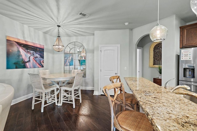 dining area with a notable chandelier, dark hardwood / wood-style flooring, and sink