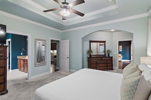 bedroom with connected bathroom, ceiling fan, a raised ceiling, light carpet, and ornamental molding