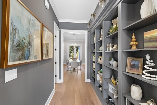 hall featuring a chandelier, light hardwood / wood-style floors, and crown molding